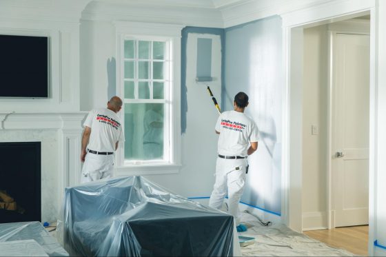 two painters in white uniforms painting the interior of a home