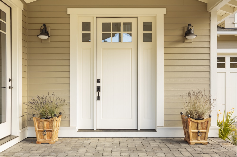 A white front door with rustic planters on either side